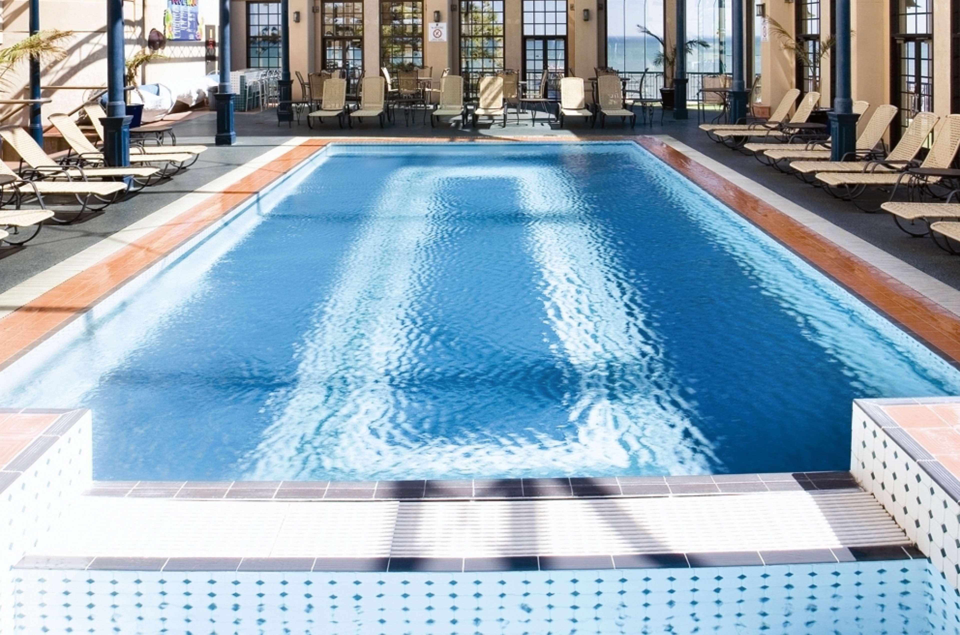 Hotel Stamford Grand Adelaide Glenelg Zewnętrze zdjęcie The photo shows an indoor swimming pool with a pristine blue surface. The pool is surrounded by a tiled deck and has lounge chairs lined up along the sides. Large windows allow natural light to flood the area, creating a bright and inviting atmospher