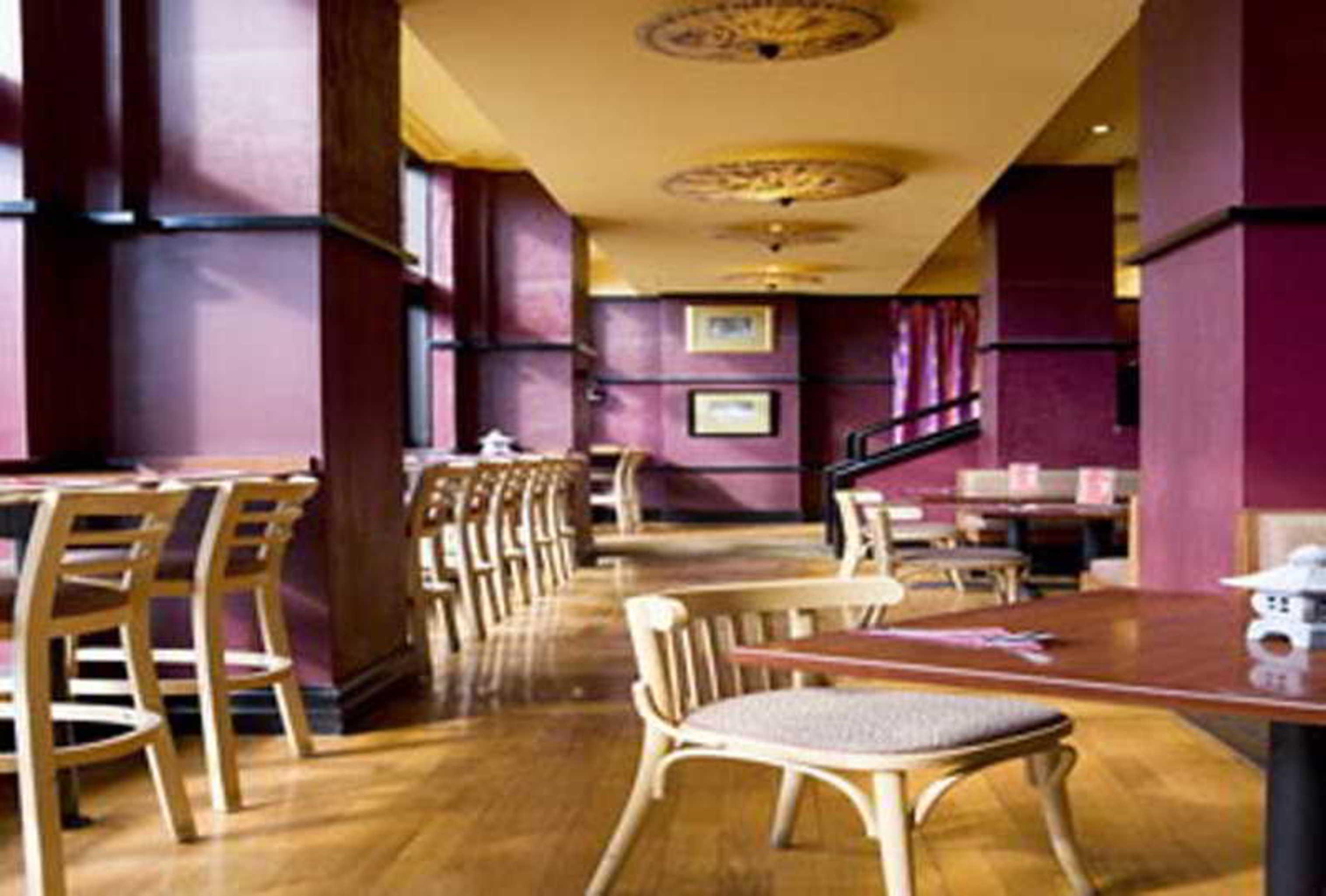 Hotel Stamford Grand Adelaide Glenelg Zewnętrze zdjęcie The photo shows the interior of a restaurant. It features wooden flooring and a warm color palette, primarily using shades of burgundy and gold. There are several wooden chairs arranged around tables, with the seating area appearing spacious and invi