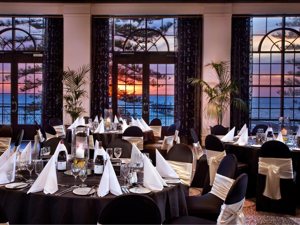 Hotel Stamford Grand Adelaide Glenelg Zewnętrze zdjęcie The photo shows an elegant dining setup inside a venue with large windows. The tables are adorned with black tablecloths and white napkins arranged in a stylish manner. Each table has glassware and other dining utensils placed neatly. In the backgrou